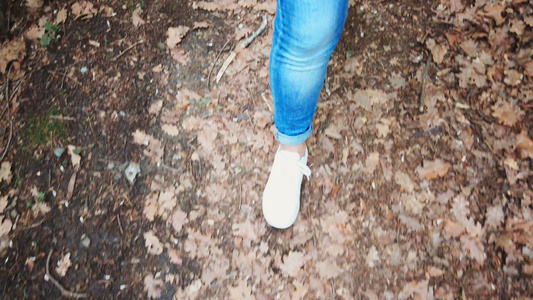 穿着运动鞋和牛仔裤跟踪拍摄镜头;在森林中行走的妇女视频