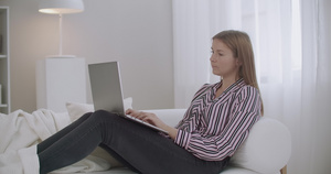 年轻妇女正在家中沙发上浏览互联网使用笔记本电脑14秒视频
