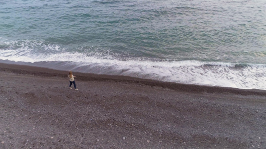女青年在海边行走随波逐流空中观察无人机沿模型飞来飞去视频