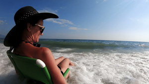 在海滩上坐着草帽的迷人女人24秒视频