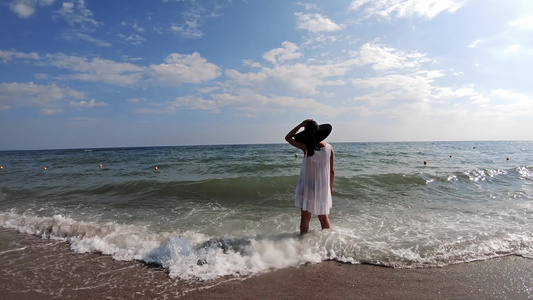 身着美丽的白裙子站在海滩海岸上站着的快乐年轻女子视频
