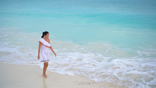 在浅水中行走白沙滩上一个女人的顶端风景视频