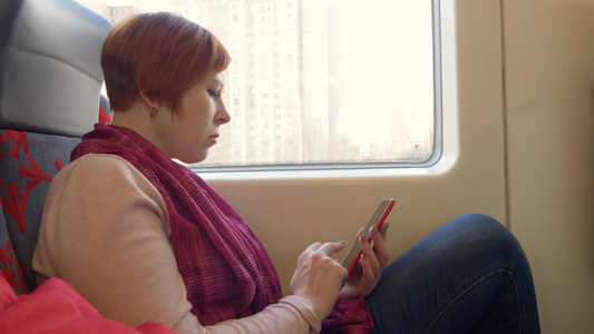 女人在火车上用她的智能手机阅读视频