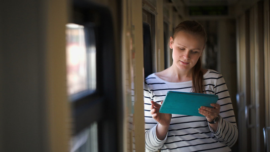 站在火车走廊窗户窗边的有垫子的年轻女子视频