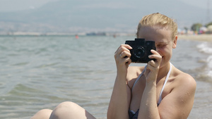 微笑着的女士在海边用她的旧相机拍照15秒视频