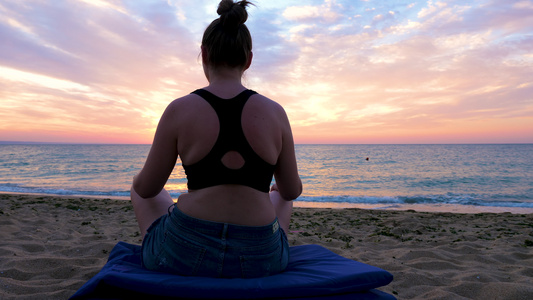 女人在海边做瑜伽在日出的海滩上看着一幅景色的全景视频