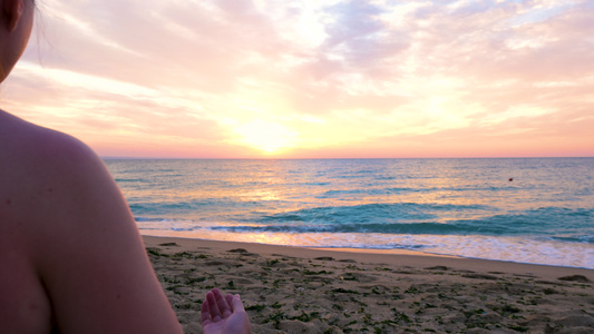 女人坐在沙滩上做瑜伽在日出视频