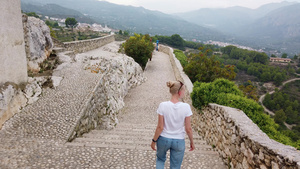金发女人在欧洲山中中世纪城堡的防守墙上行走21秒视频