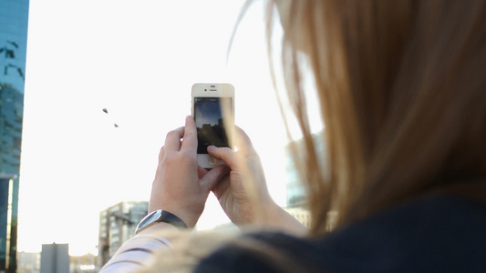 妇女用她的手机拍下城市照片视频