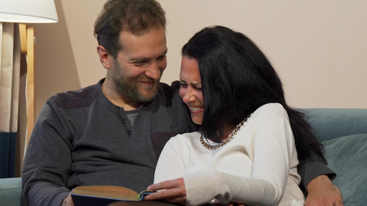 已婚已婚成熟的情侣在阅读一本书时一起大笑视频