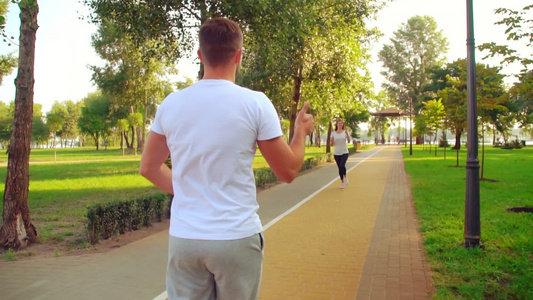 女孩和男孩跑不同方向在公园的赛道上视频