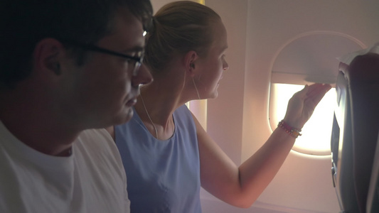 女性和男性向飞机窗外看视频