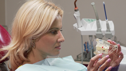 成年女子对着镜头微笑在诊所装有牙科模具视频