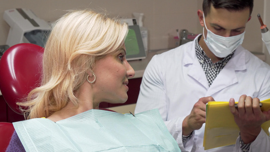 快乐的女病人在牙医面前坐在牙科椅子上露出拇指视频