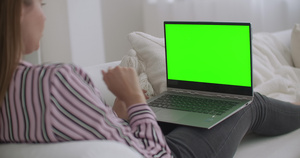 年轻轻松的女性正在使用带绿屏的笔记本电脑来进行色度14秒视频