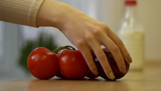 年轻妇女在厨房把新鲜蔬菜西红柿和洋葱放在桌上视频