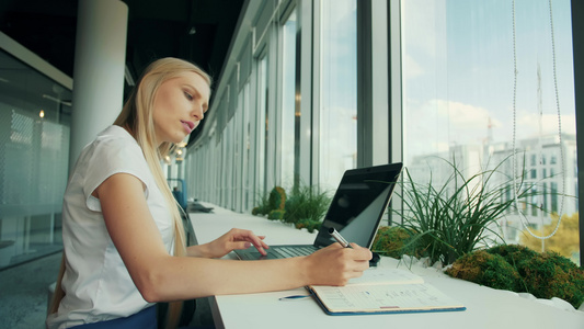 有膝上型计算机和文件的正式妇女在现代办公室靠近窗户视频