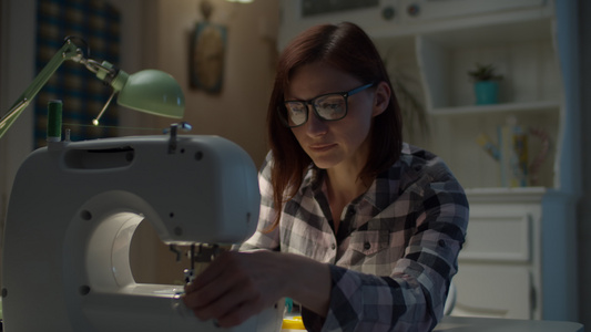 30名戴眼镜的妇女在家中缝制缝纫机上戴保护面罩在家视频