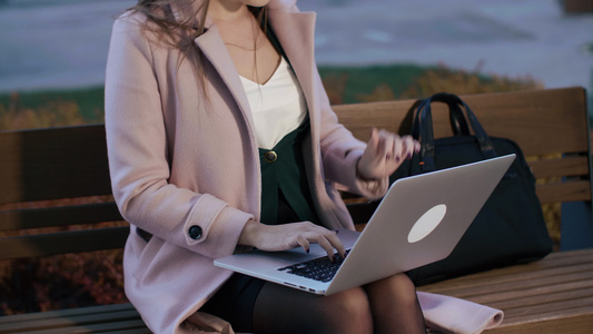 使用笔记本电脑坐在市公园板凳上的女美容博客视频