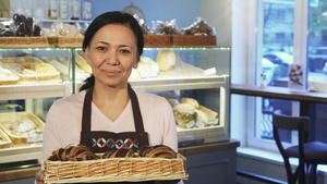 装满一篮子羊角面包的成熟女性面包师在她的店铺上摆着6秒视频