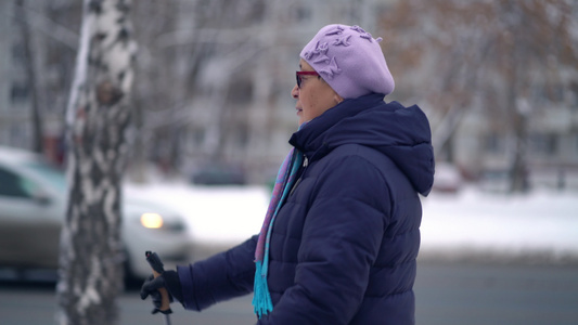 活跃的老年妇女用登山杖训练北欧式行走冬天在户外练习视频