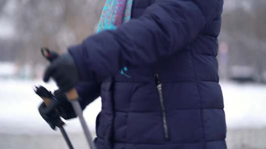 活跃的老年妇女用登山杖训练北欧式行走冬天在户外练习视频