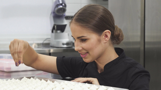 美丽的女性糕点厨师装饰带有椰子片的蛋白环球视频