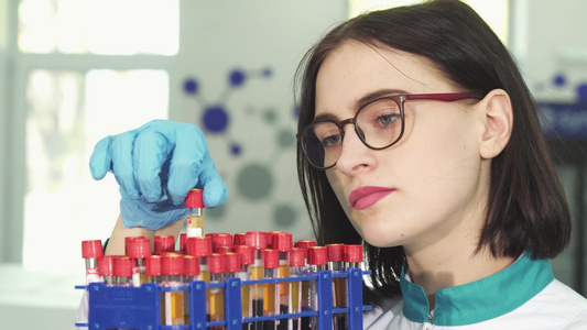 年轻女青年研究员用血液样本检查试管和血液样本视频