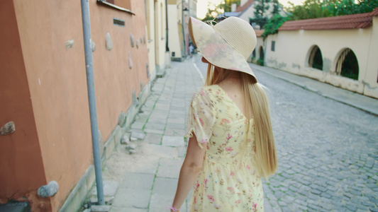 穿着白帽子的漂亮女孩在城里漫步时看着摄像机看着镜头视频