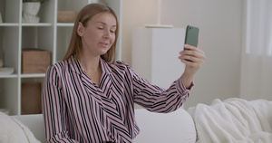年轻女性使用智能手机的视频电话坐在家中14秒视频