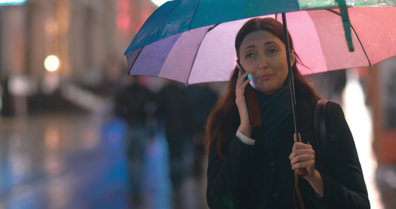 带着雨伞的年轻女子在电话里说话视频