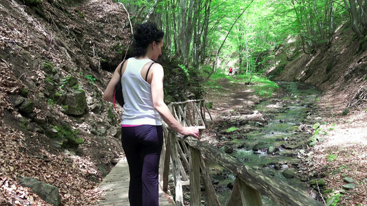 迷人的性感女性喜欢在雨林小径上徒步旅行站在靠近泉水视频