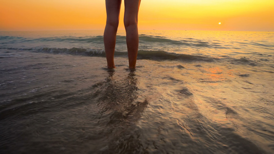 海滩日落时女人的脚被海浪溅起在美丽的海滩上海水溅在视频
