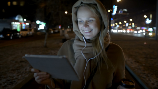 快乐的女子在夜晚城市看平板电脑视频
