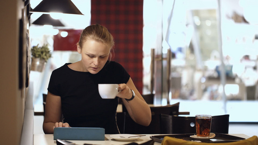 坐在咖啡馆的青年妇女有垫子和喝咖啡视频