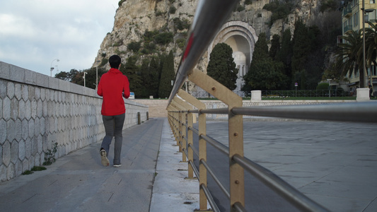 穿着红色运动运动衫灰色短裤和运动鞋在街上慢跑的妇女视频