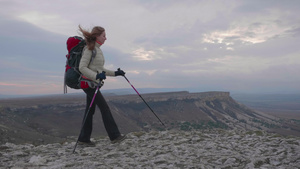 带着背包和徒步杆的年轻登山女青年正在岩石边缘行23秒视频