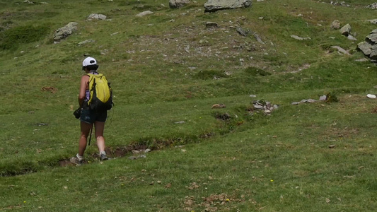 一个女人带着背包在山上漫步慢动作视频