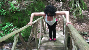 年轻运动女青年在森林桥上做俯卧撑16秒视频