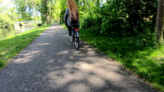后背看女人的金发在风中吹着头发骑着自行车视频