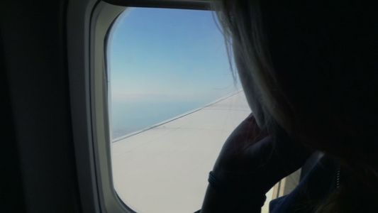 女人在飞机上向窗外看视频