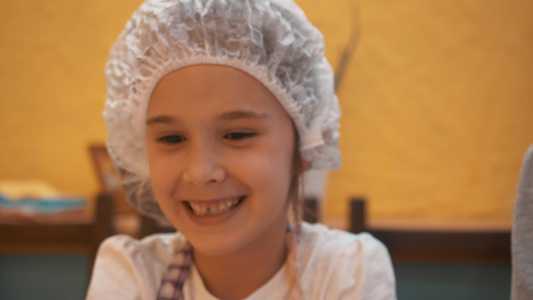 戴一次性帽子的小女孩在厨房里玩生面团快乐的女孩在烹饪视频