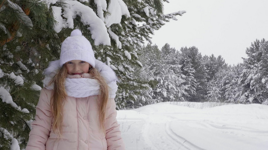 在冬季森林积雪中快乐的年轻女孩仰望着摄影机视频