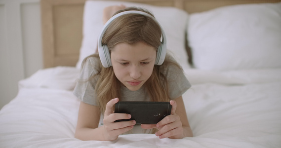 少女正在用智能手机上网从网站上阅读信息放学后躺在家里视频