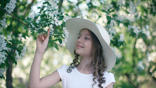 浪漫的女孩在盛开的果园里嗅着苹果树的花朵春天戴着白视频