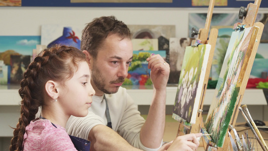 成熟的男性画家帮助他可爱的女儿画一幅画视频