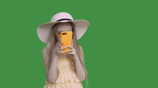 穿着暑期帽子和服装的少女正在浏览电话视频