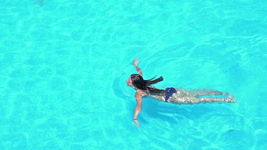 女孩在游泳池游泳4k航空飞行拍摄视频