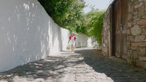 旅游女孩在阳光明媚的街道上行走在夏日老城镇充满岩壁10秒视频