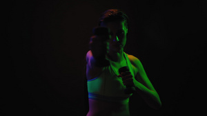 健身女孩在霓虹灯下用哑铃锻炼身穿运动上衣伸展颈部肌肉39秒视频